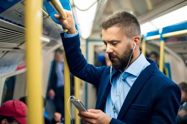 Un homme d'affaires dans le métro en train d'écouter un podcast sur l'apprentissage de l'anglais. Le sujet, c'est comment mieux comprendre l'anglais.